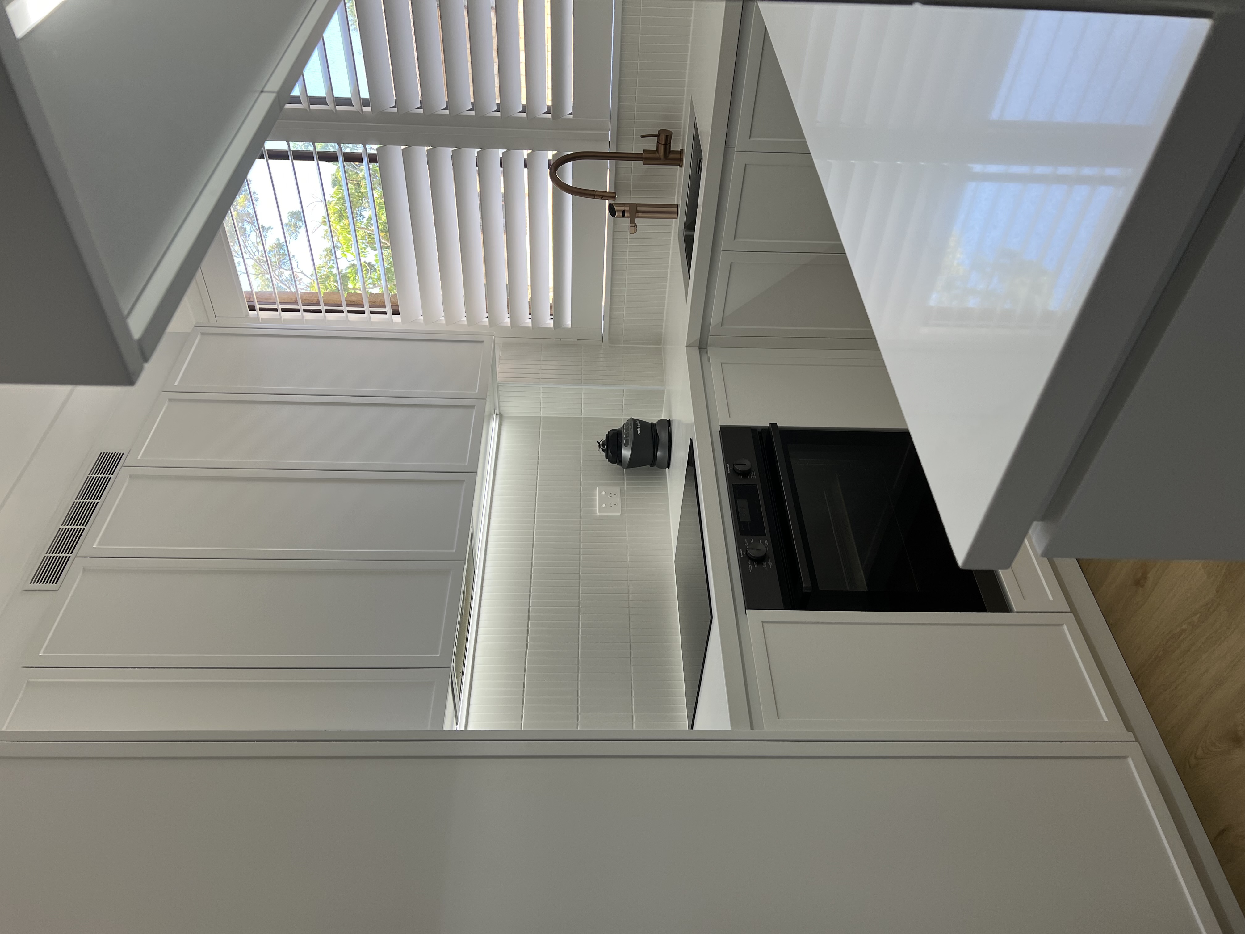 Modern white kitchen with custom DJR cabinetry, LED lighting, and timber accents